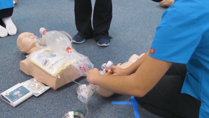 A Person Practicing CPR on A Training Mannequin Surrounded by Medical Training Equipment on The Floor